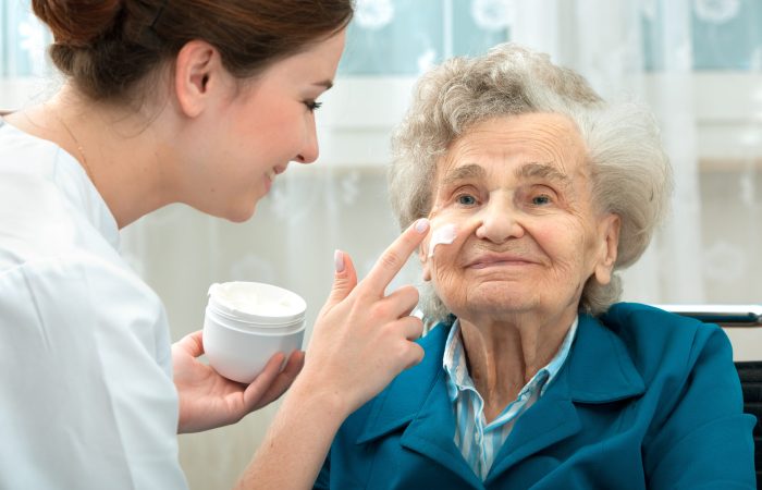 Nurse assists an elderly woman with skin care and hygiene measures at home